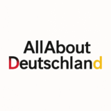 Logo for AllAboutDeutschland travel blog featuring clean black text and the German flag colors — red, black, and gold.