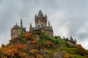cochem village Stunning view of Reichsburg Castle in Cochem, Germany, surrounded by fall foliage.