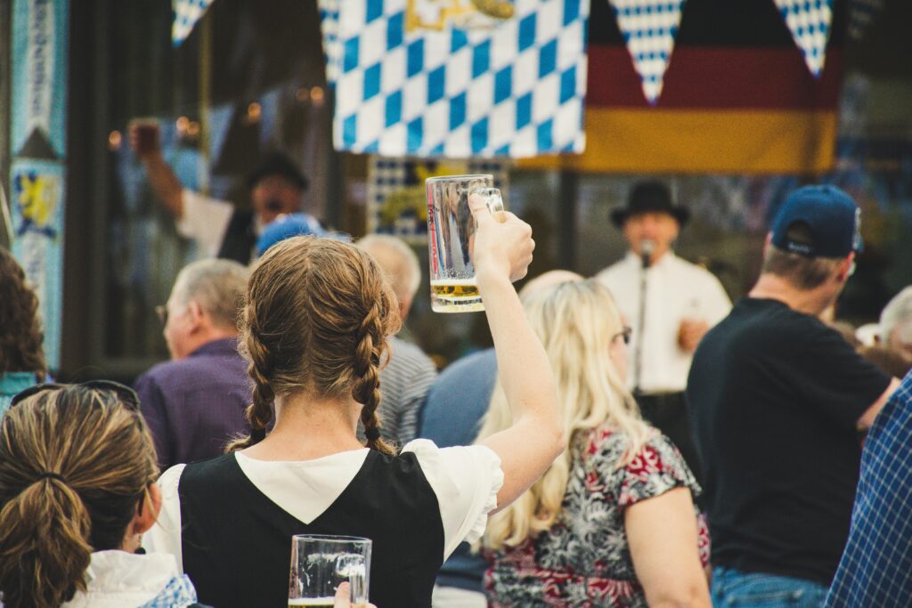 Oktoberfest Munich what to wear A lively crowd enjoys Oktoberfest outdoors with beer mugs raised. Perfect for festival season visuals.