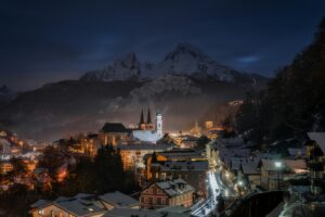 Berchtesgaden village A picturesque winter night view of Berchtesgaden, Germany, with snow-covered rooftops and majestic mountains in the background.